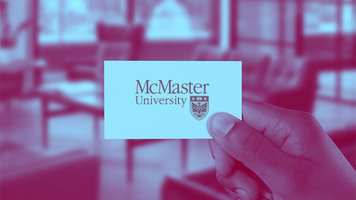 A hand holding up a card with the McMaster University logo.